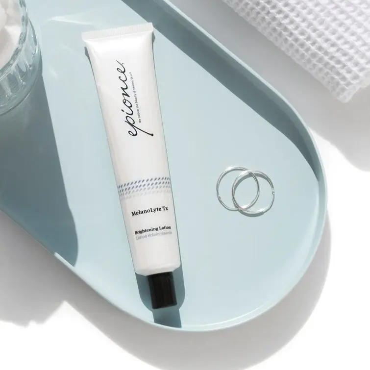 A white tube of Epionce MelanoLyte Tx cream sitting on top of a blue tray.