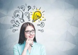 woman smiling thinking with hand on chin looking up at light bulb