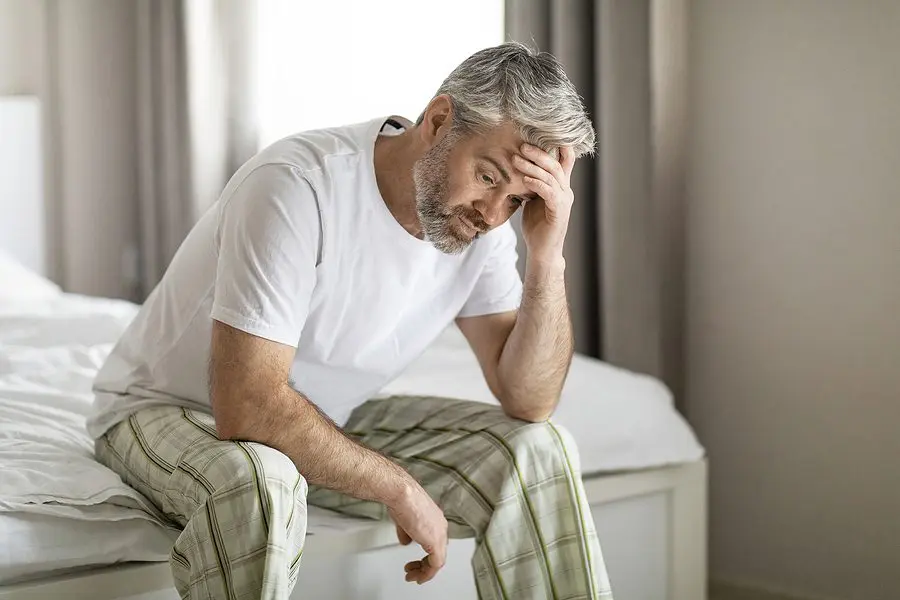 mid age man upset sitting on bed