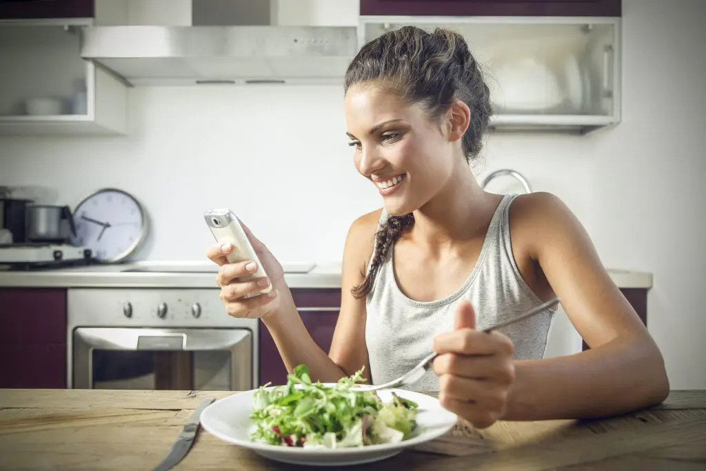 Woman looking at Stelo app while eating a salad