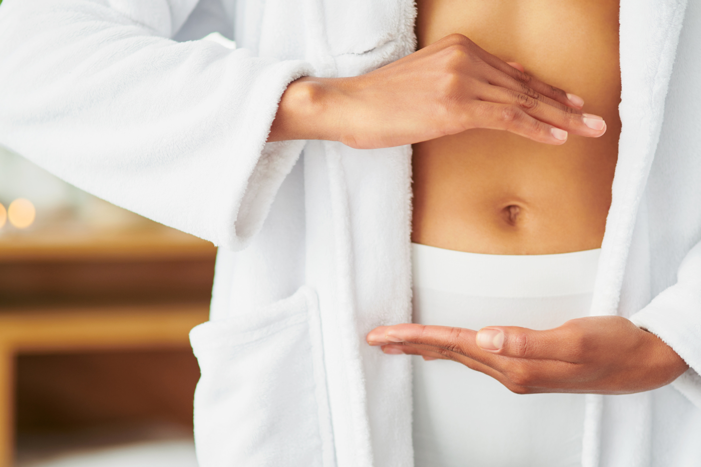 Woman in a robe framing her belly to signify gut health.
