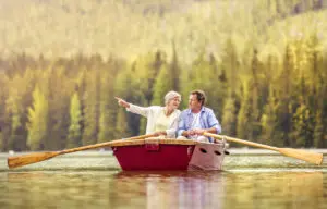 Senior couple paddling on boat with mountains in background