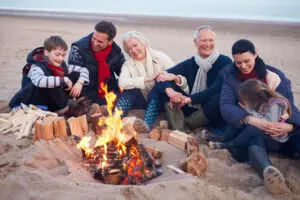 Multi Generation Family Sitting By Fire On Winter Beach Representing boosted immune systems close to family
