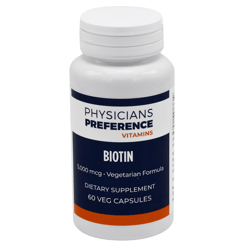 A bottle of biotin pills on a green background