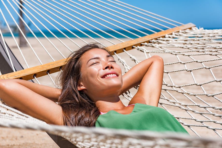 A woman laying in a hammock on the beach.