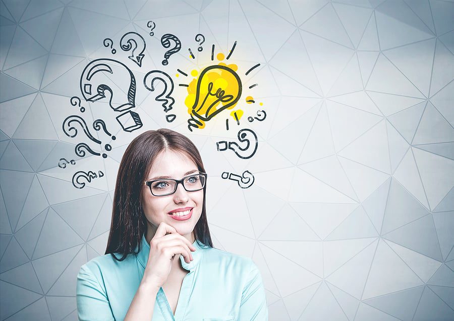 woman smiling thinking with hand on chin looking up at light bulb