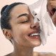 A woman is getting her face washed with a towel.