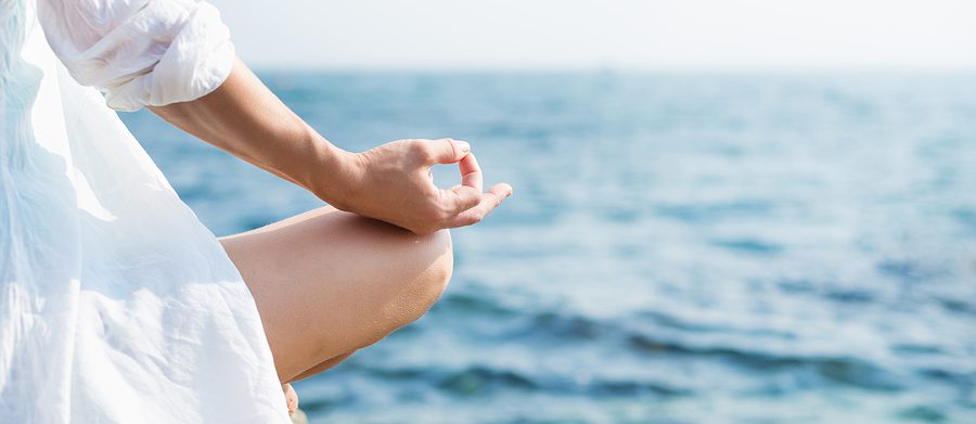 woman in white meditating by the sea