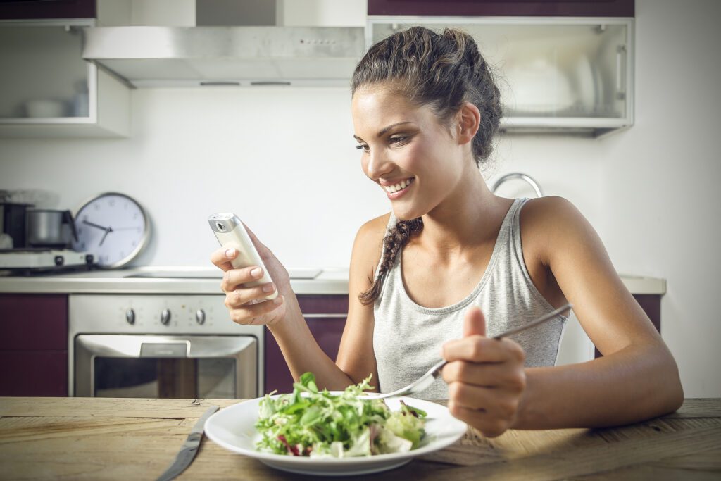 Woman looking at Stelo app while eating a salad