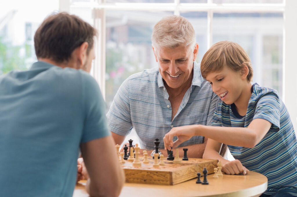 Grandfather teaches grandson how to play chess because of cognitive support supplements.