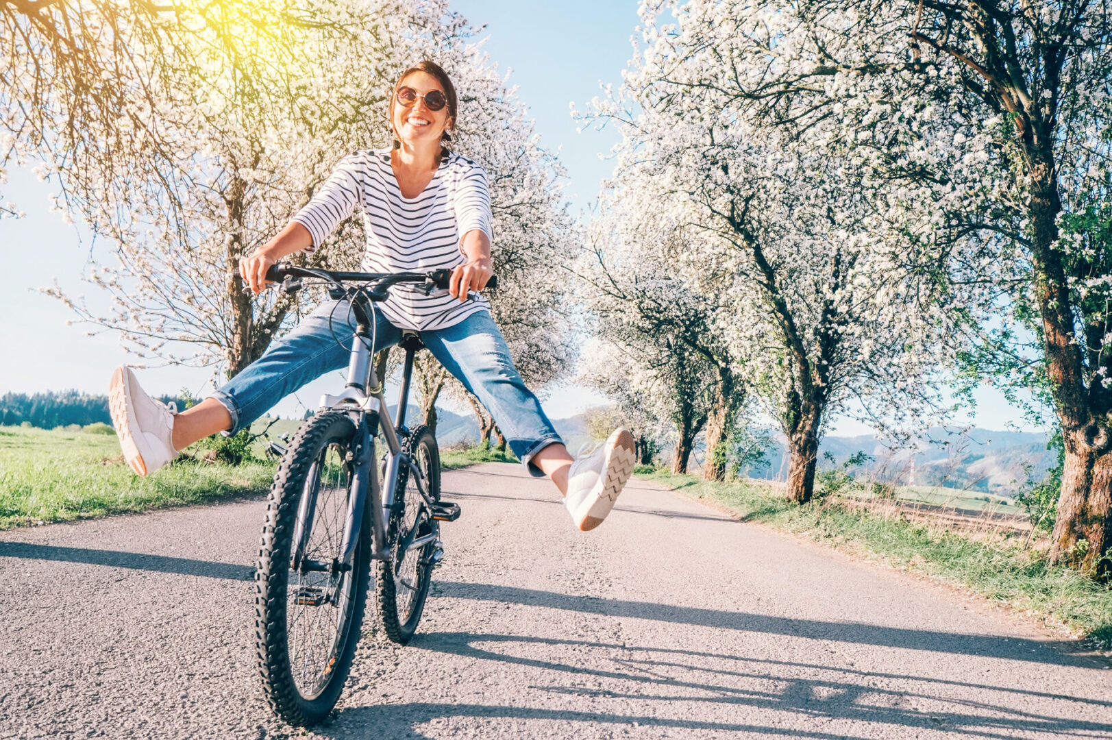 Woman riding a bike in the spring with flowery trees all around, with a healthy immune system.