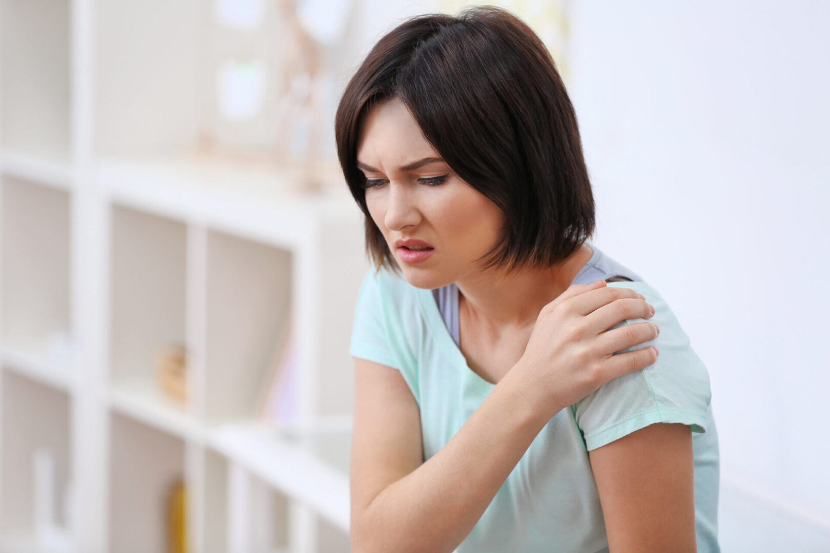 Woman gripping her shoulder who has joint stiffness and needs nutrition support