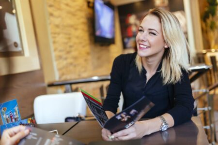 A woman holding a menu about to order not worried about food since she will be taking digestive enzymes.