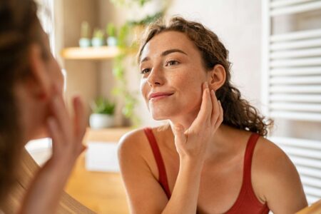 Woman touching her face to represent the gut-skin connection and skin support from within.