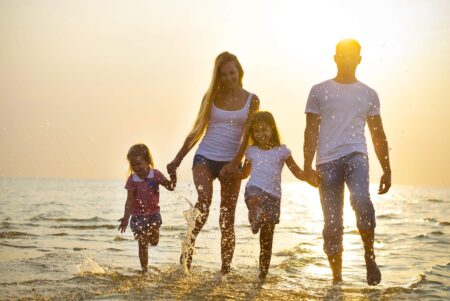 Family walking on beach in summer - Summer fatigue causes and hydration support