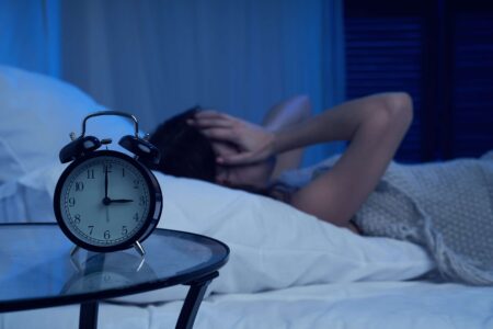 Woman awake in bed at 3 a.m., illustrating the connection between sleep and blood sugar.