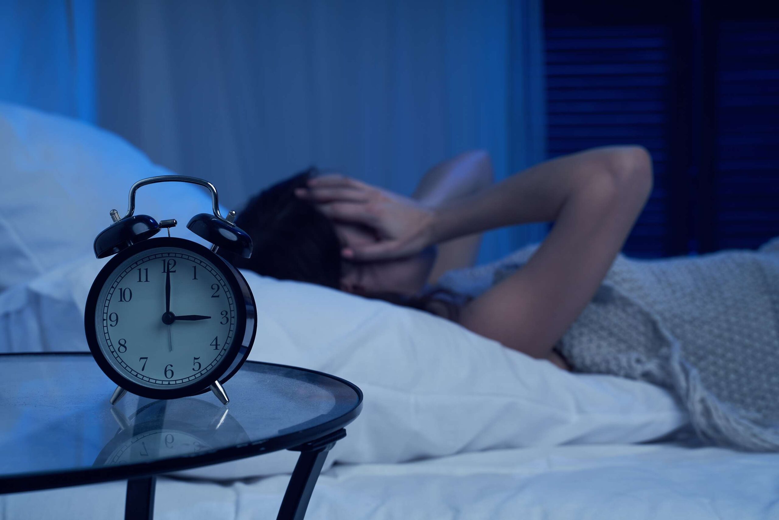 Woman awake in bed at 3 a.m., illustrating the connection between sleep and blood sugar.
