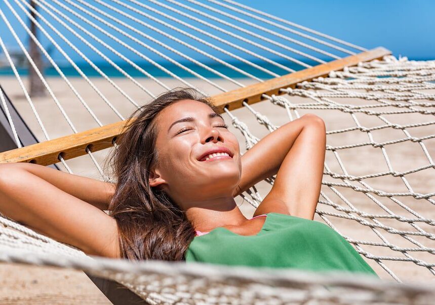 A woman laying in a hammock on the beach.