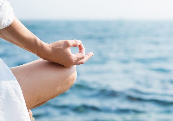 woman in white meditating by the sea