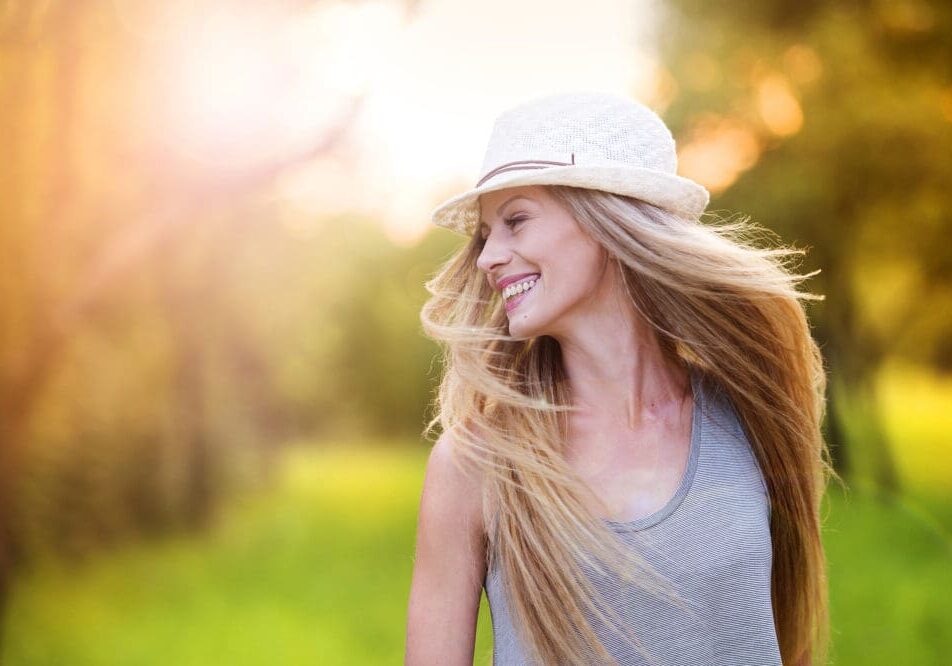 Beautiful woman outside in a park. Attractive young woman, with long flowing hair, enjoying her time outside in park with sunset in background.