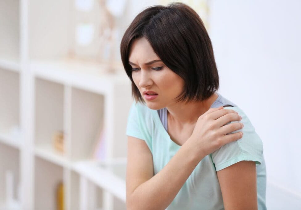 Woman gripping her shoulder who has joint stiffness and needs nutrition support