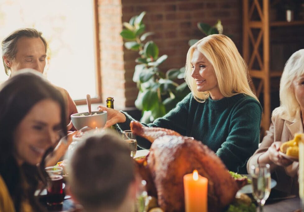 Photo of full family gathering thanksgiving feast served dinner chatting starting meal house evening living room indoors keeping in mind healthy holiday eating tips.